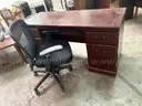 chocolate brown wooden desk with four drawers and black office chair