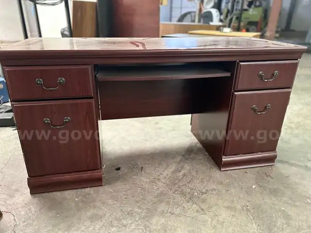 chocolate brown wooden desk with four drawers and black office chair