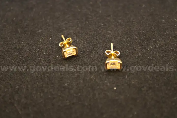Pair of gold colored stud earrings with a clear stone