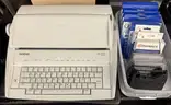 Brother ML 100 Standard typewriter with lid, various ribbons and corrective film ribbons, and cushioned pad (works!)