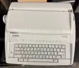 Brother ML 100 Standard typewriter with lid, various ribbons and corrective film ribbons, and cushioned pad (works!)