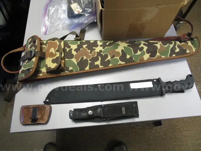 (1) USED MACHETE IN BLACK SHEATH; (1) USED SOG KNIFE IN BLACK SHEATH; (1) USED LEATHER HOLSTER; (1) USED CAMO HOLSTER